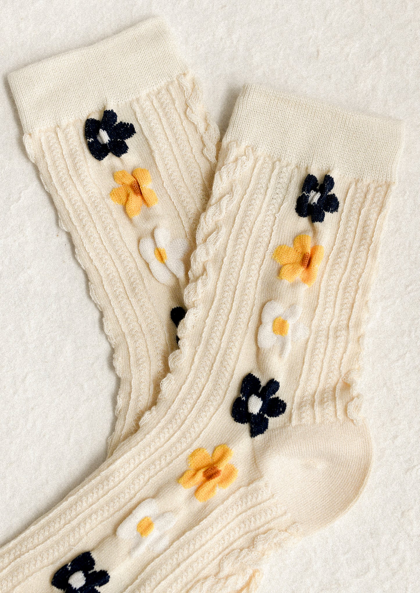 A pair of cream socks with yellow, navy and white floral pattern.