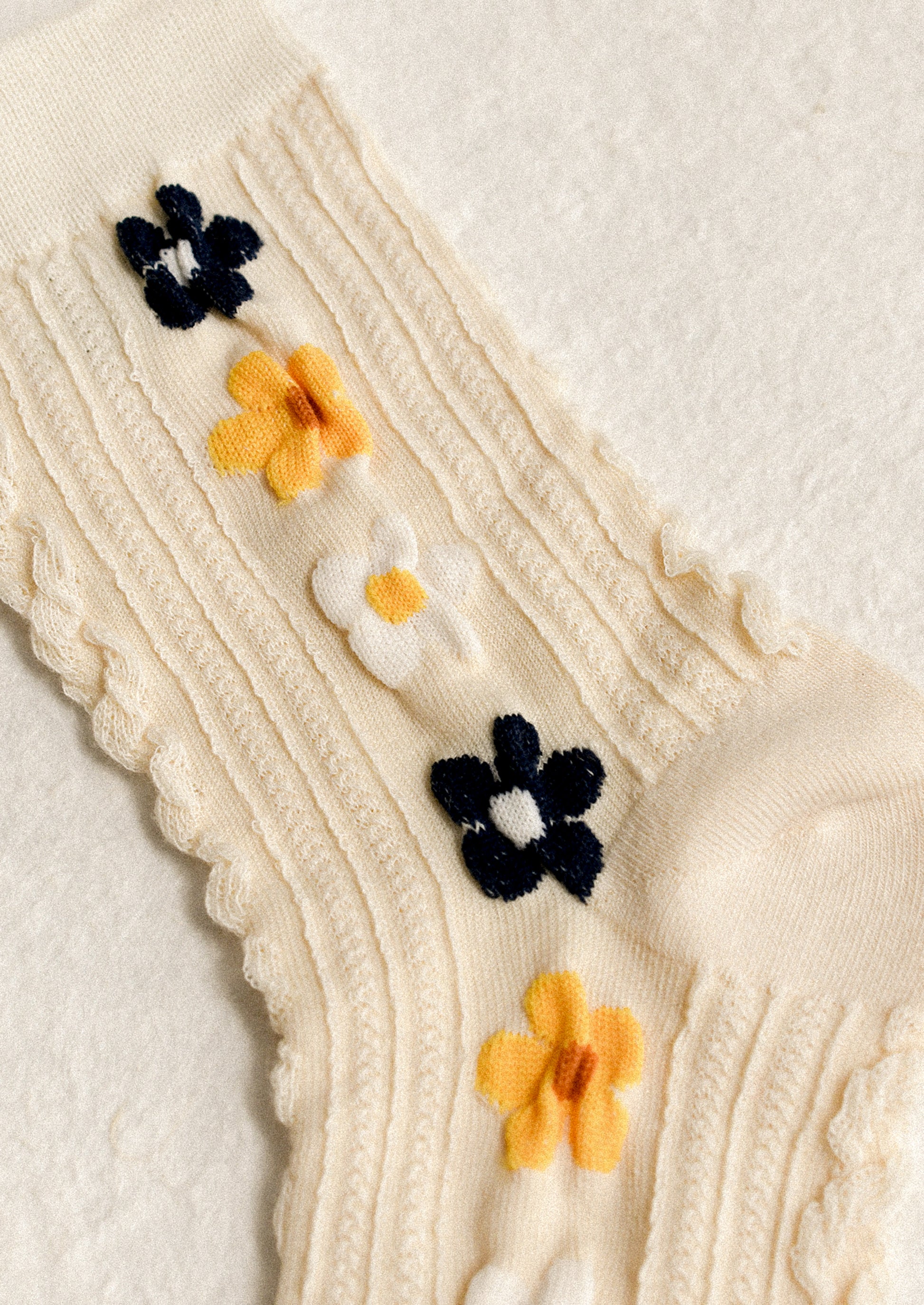 A pair of cream socks with yellow, navy and white floral pattern.
