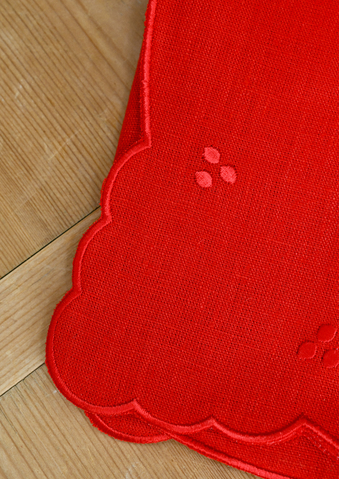 A bright red linen napkin with scalloped embroidery details.
