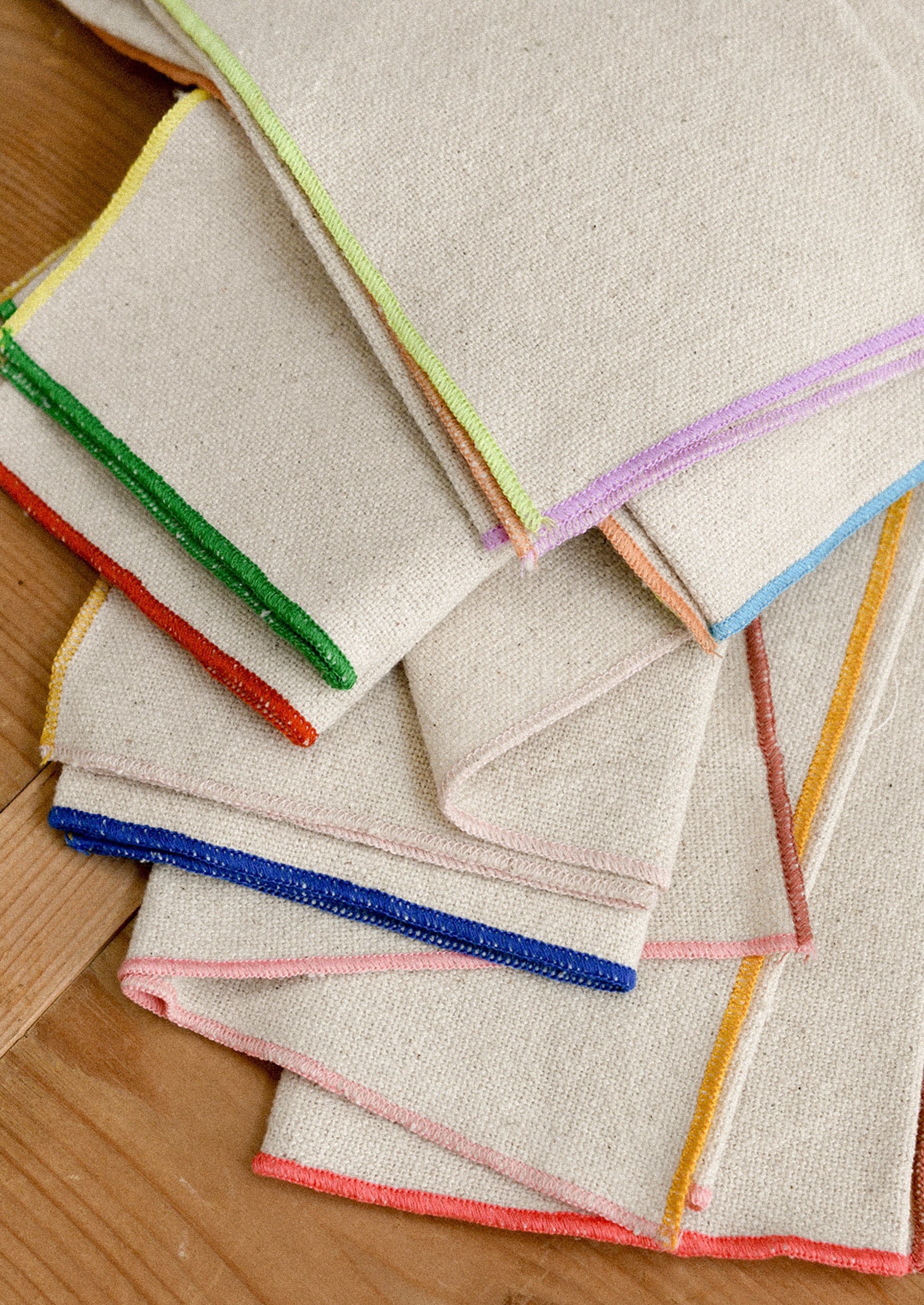 Set of folded napkins with colorful edges on a wooden surface