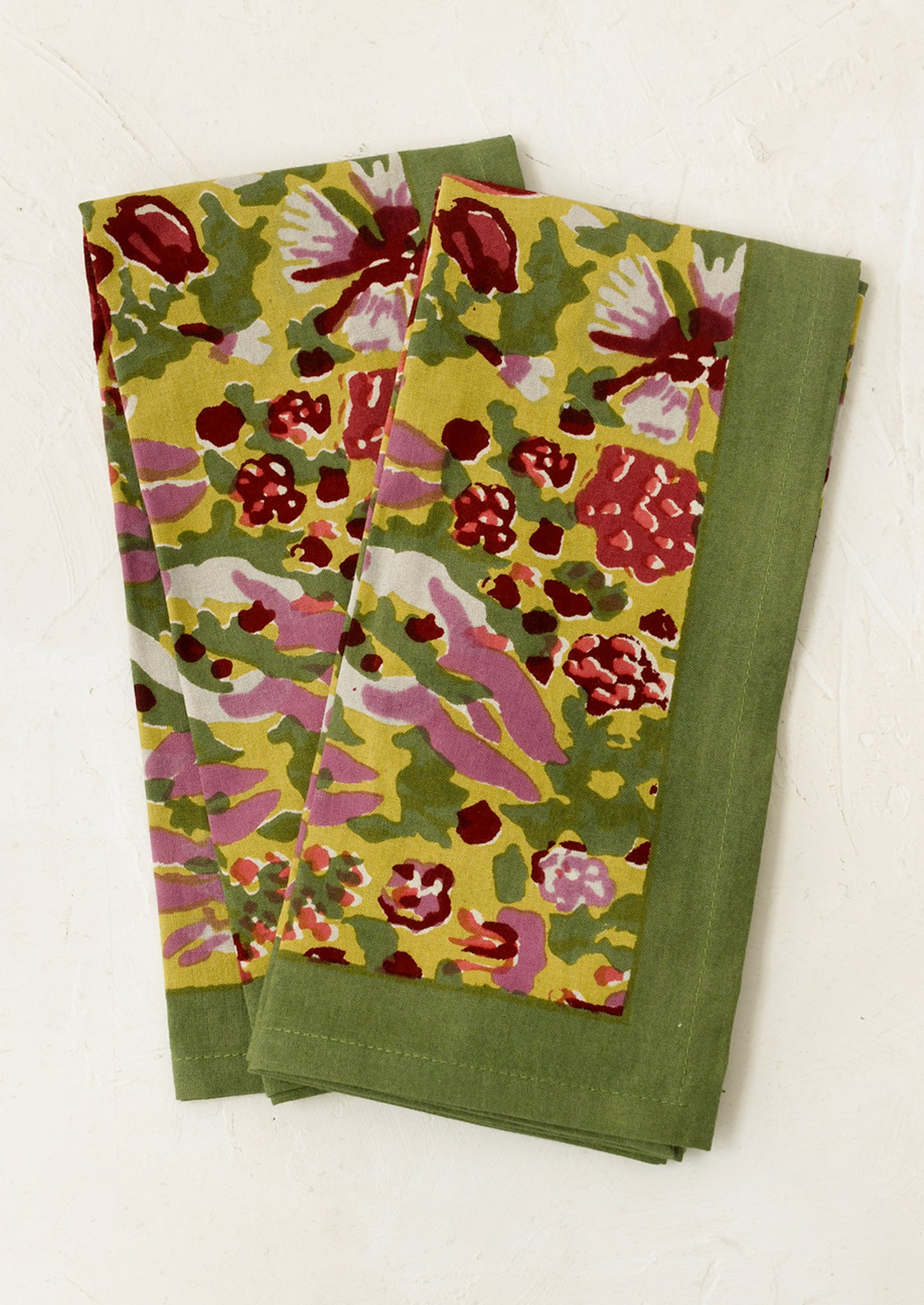 A pair of napkins in green block printed floral pattern.