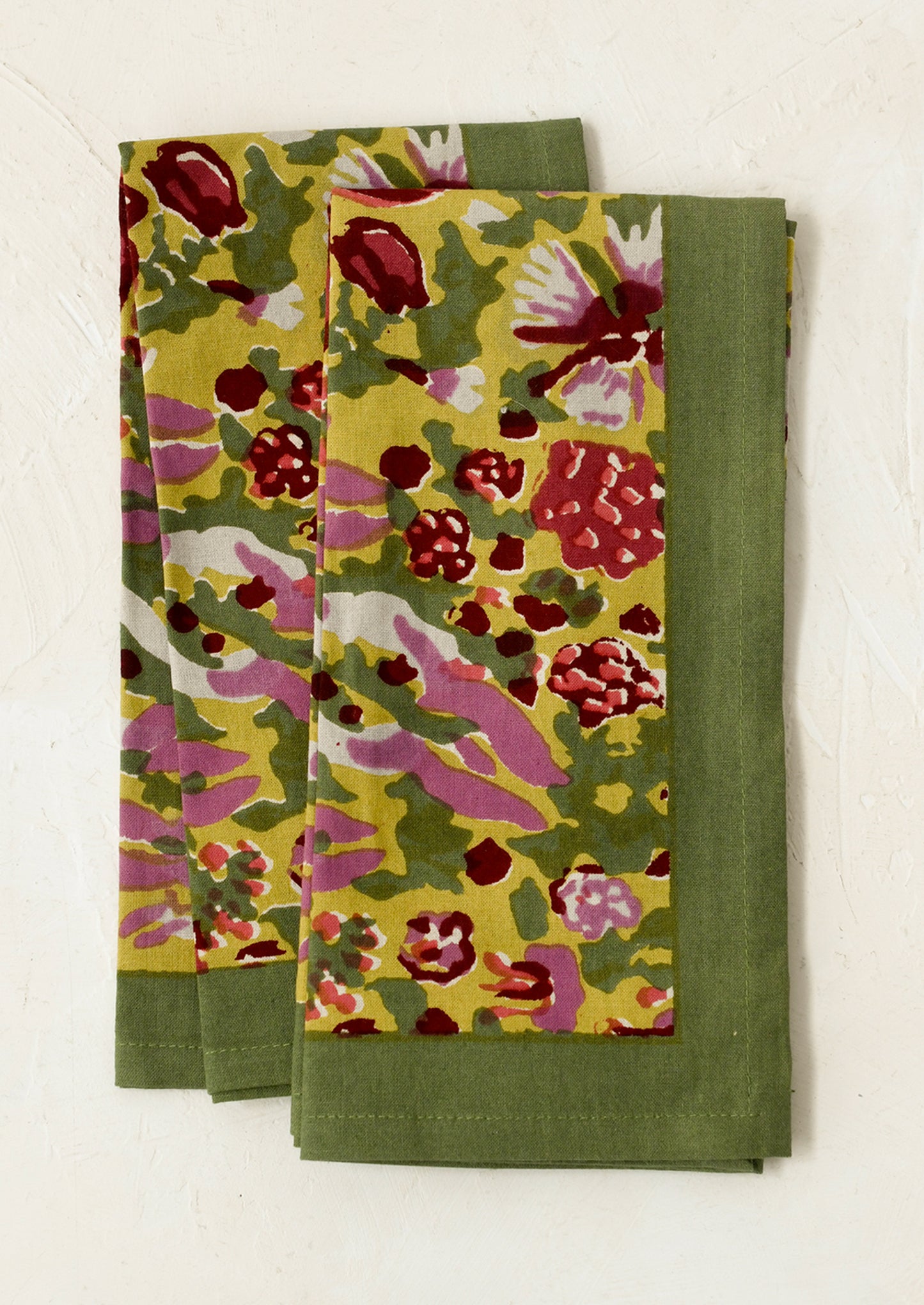 A pair of napkins in green block printed floral pattern.