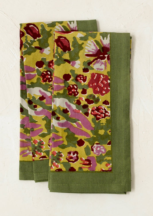 A pair of napkins in green block printed floral pattern.