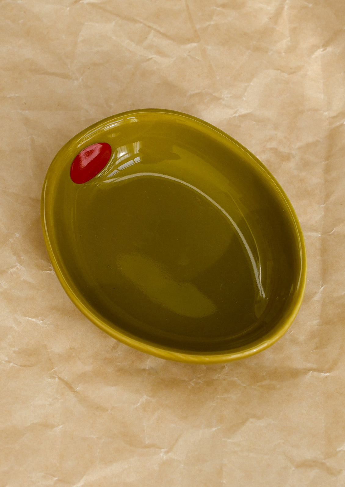 A small ceramic bowl shaped like an olive in olive green.