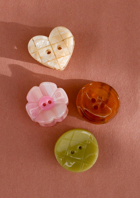 A set of four assorted mini hair claws that look like buttons.