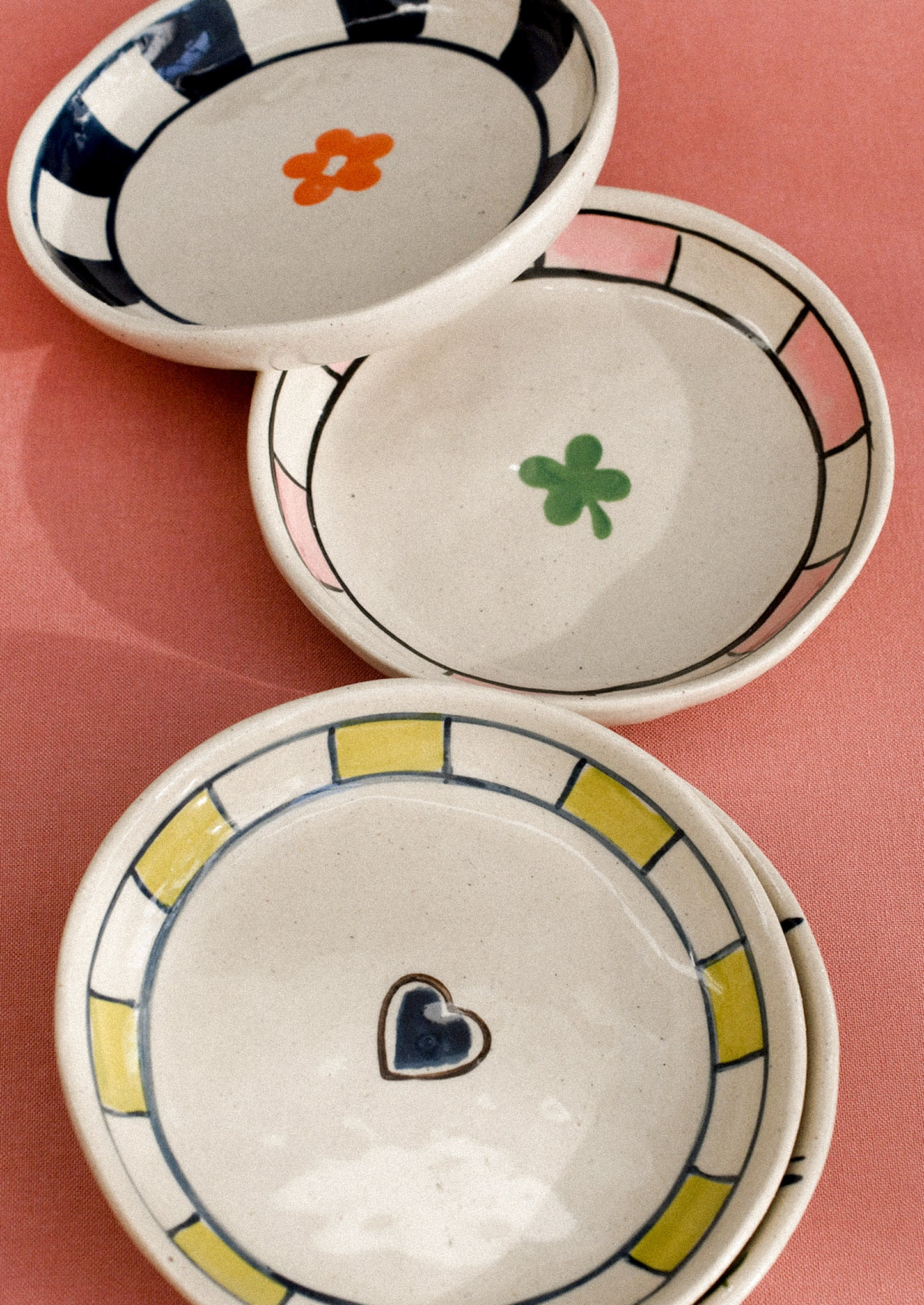 Three ceramic bowls with decorative elements on a pink background