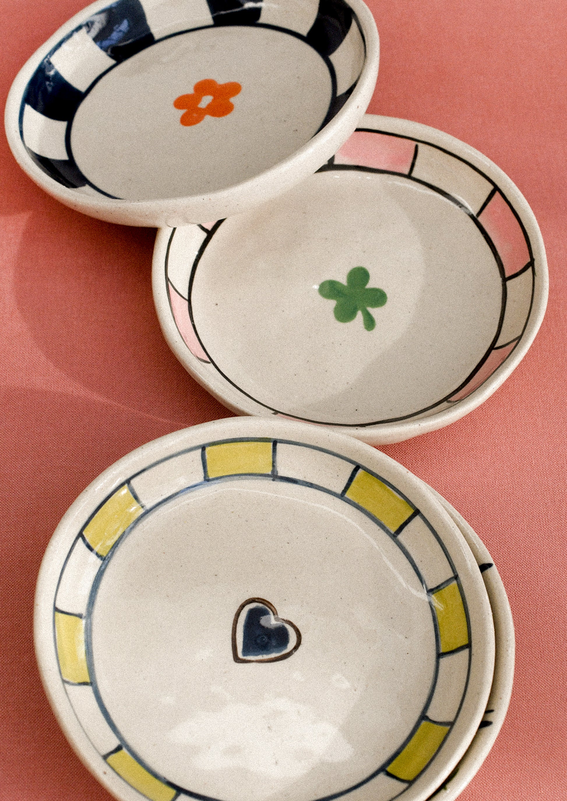 Three ceramic bowls with decorative elements on a pink background