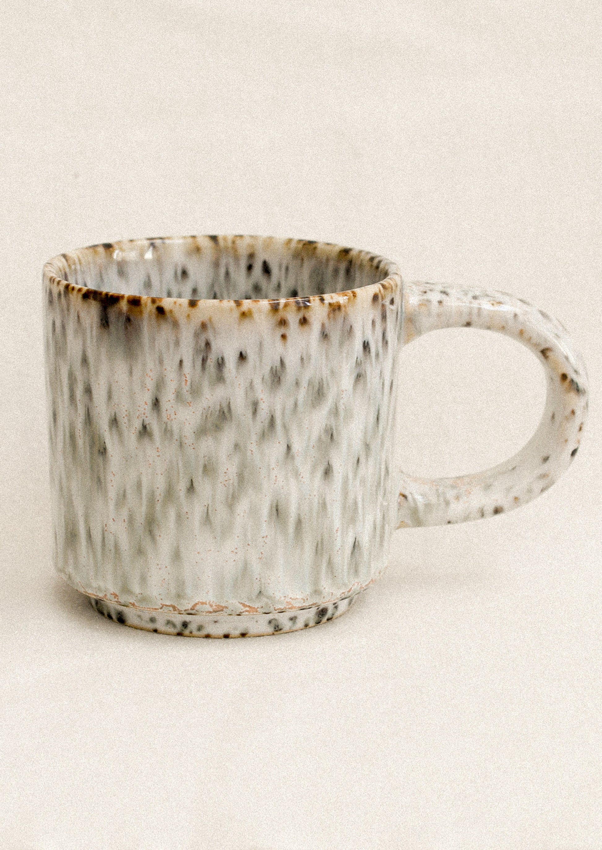Speckled ceramic mug on a beige background