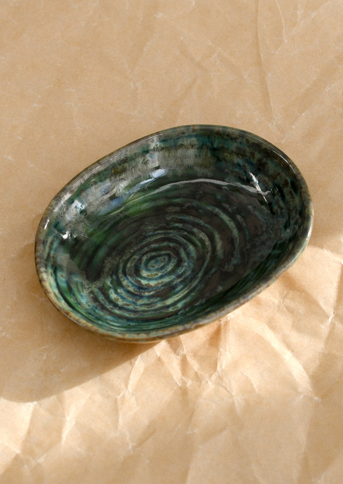 A small ceramic sauce dish in oval shape and deep emerald green reactive glaze.