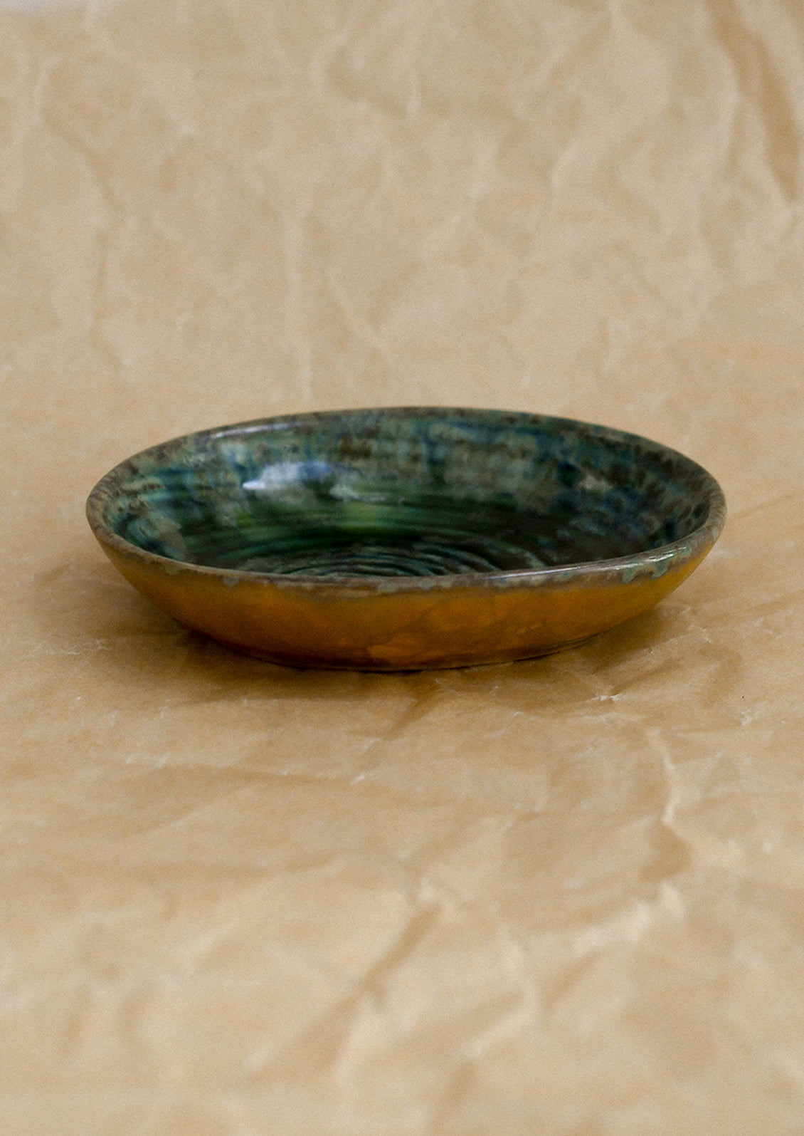 A small ceramic sauce dish in oval shape and deep emerald green reactive glaze.