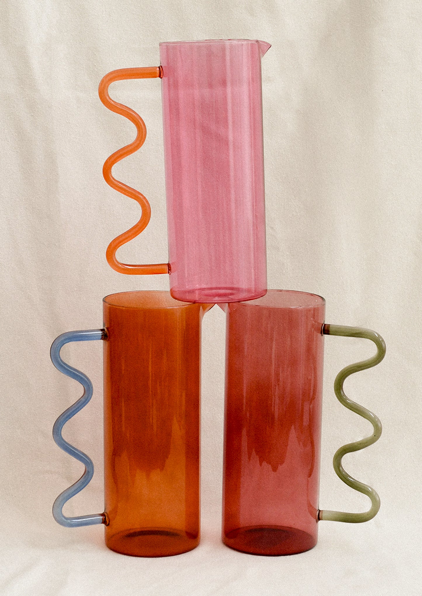 Two tone glass pitchers with squiggle shaped handles in an assortment of colors.