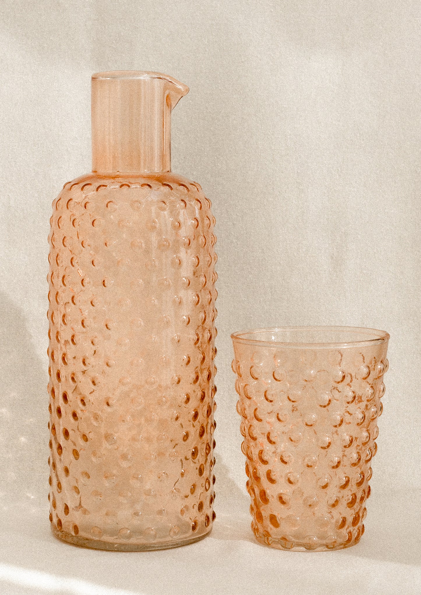 A carafe and cup set with hobnail texture in peach color.