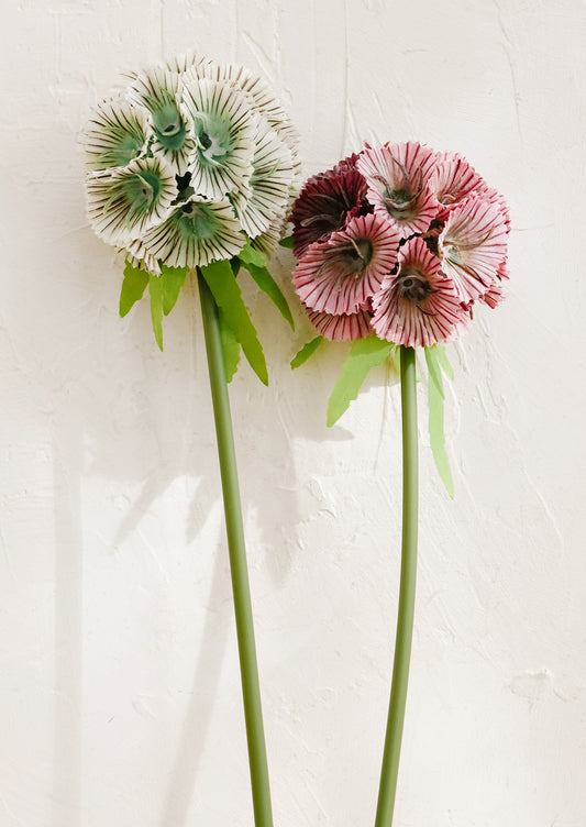 Two faux floral stems, one white and one pink, on a light background.