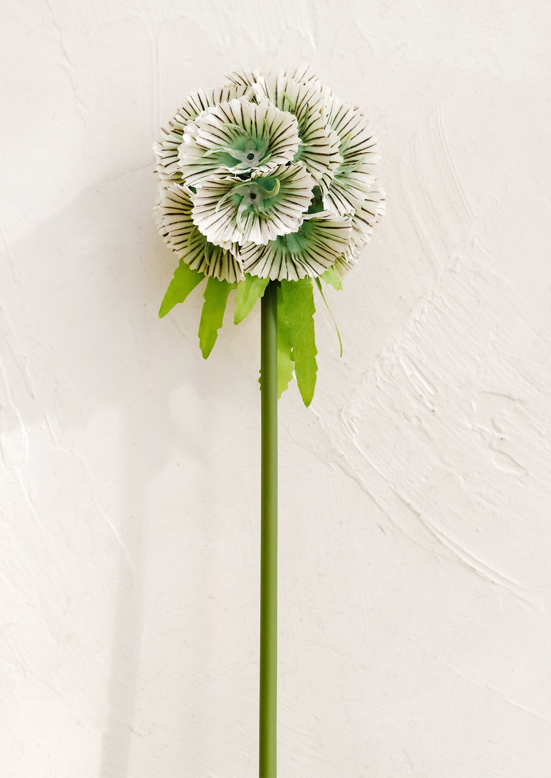 Artificial flower with green leaves on a light background