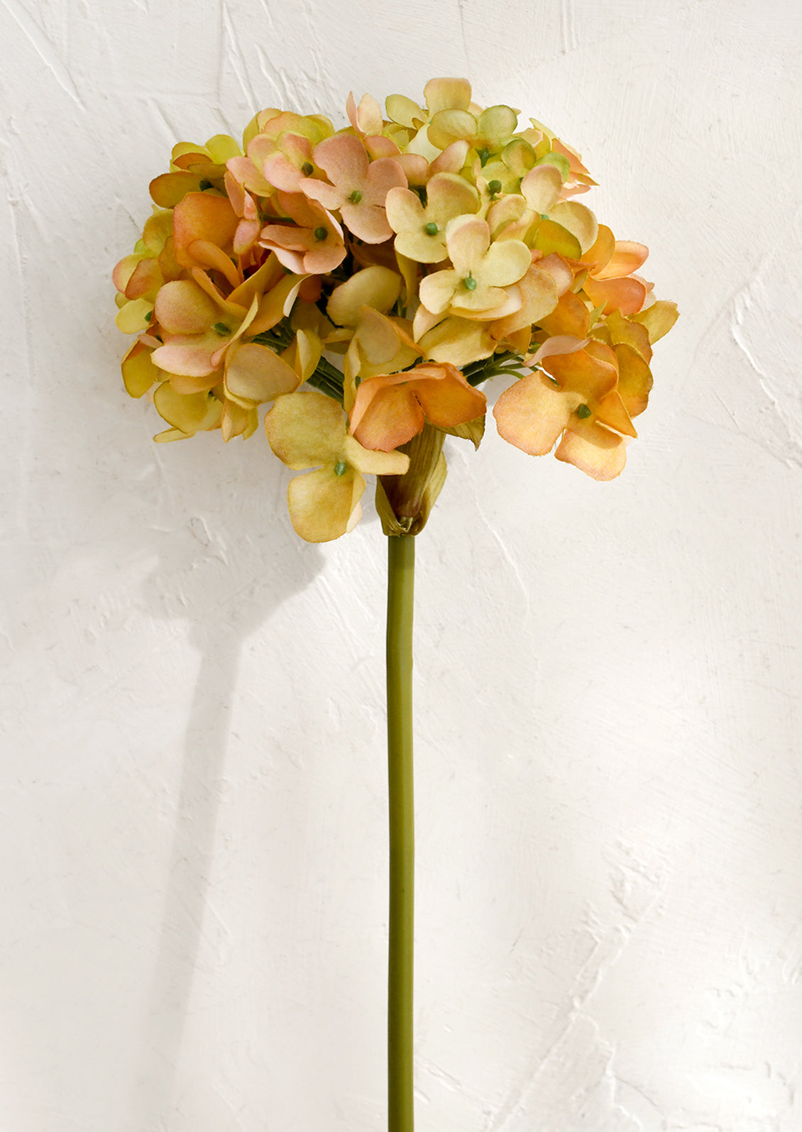 Artificial flower with peach and green flowers on a white background