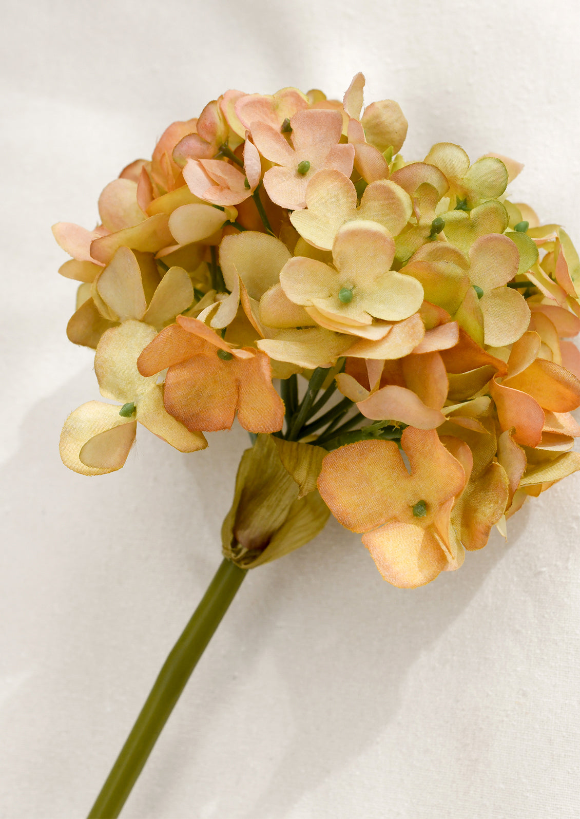 Artificial flower with peach and green flowers on a white background