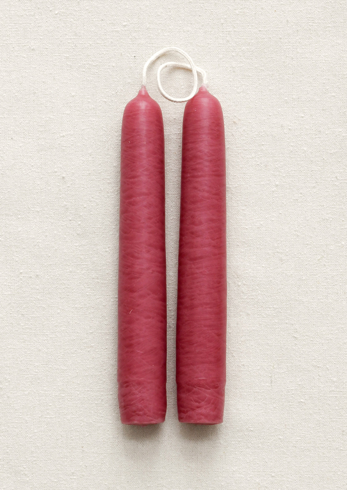 Two pink candles on a textured white surface