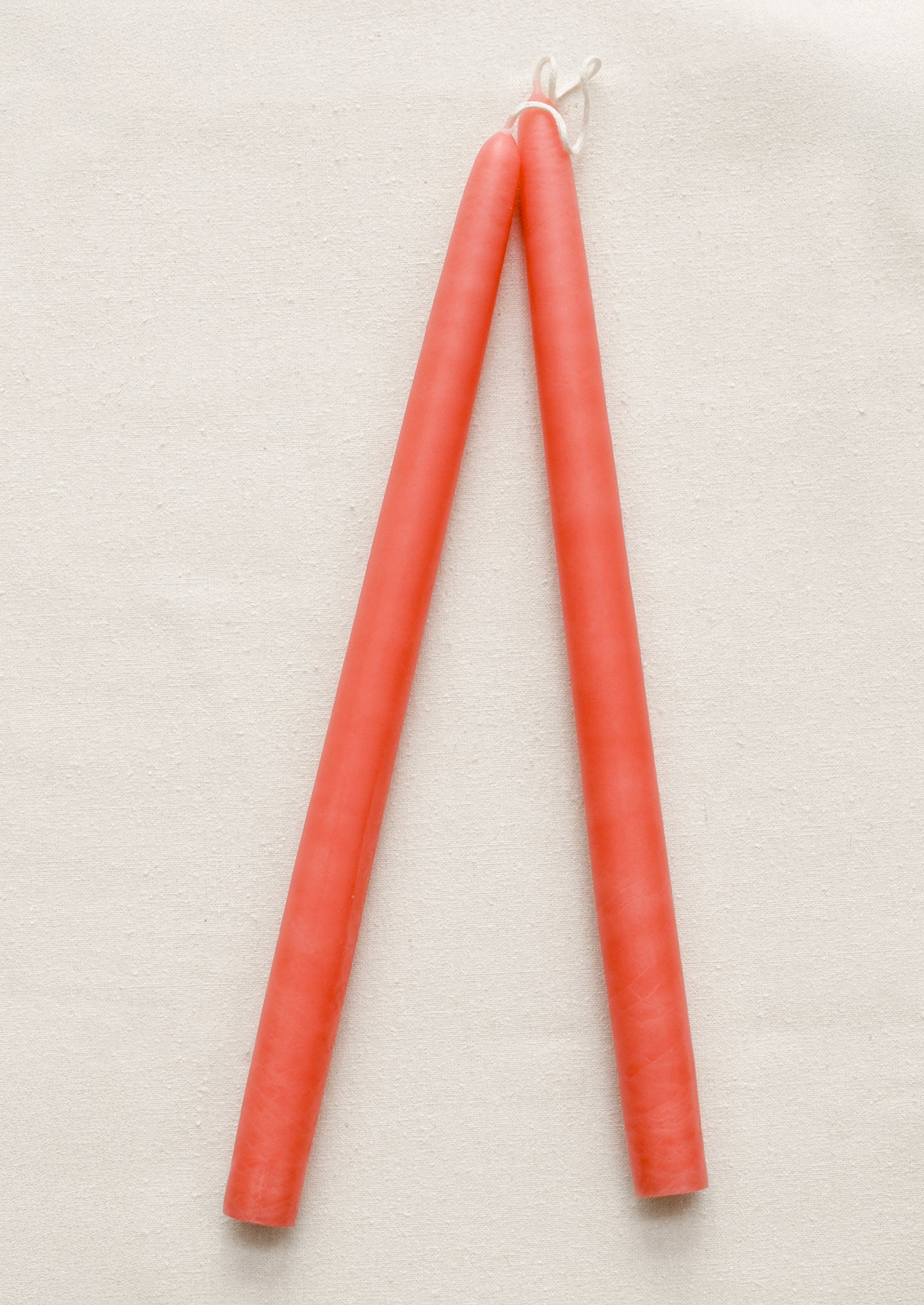 Two peach candles tied together on a beige background