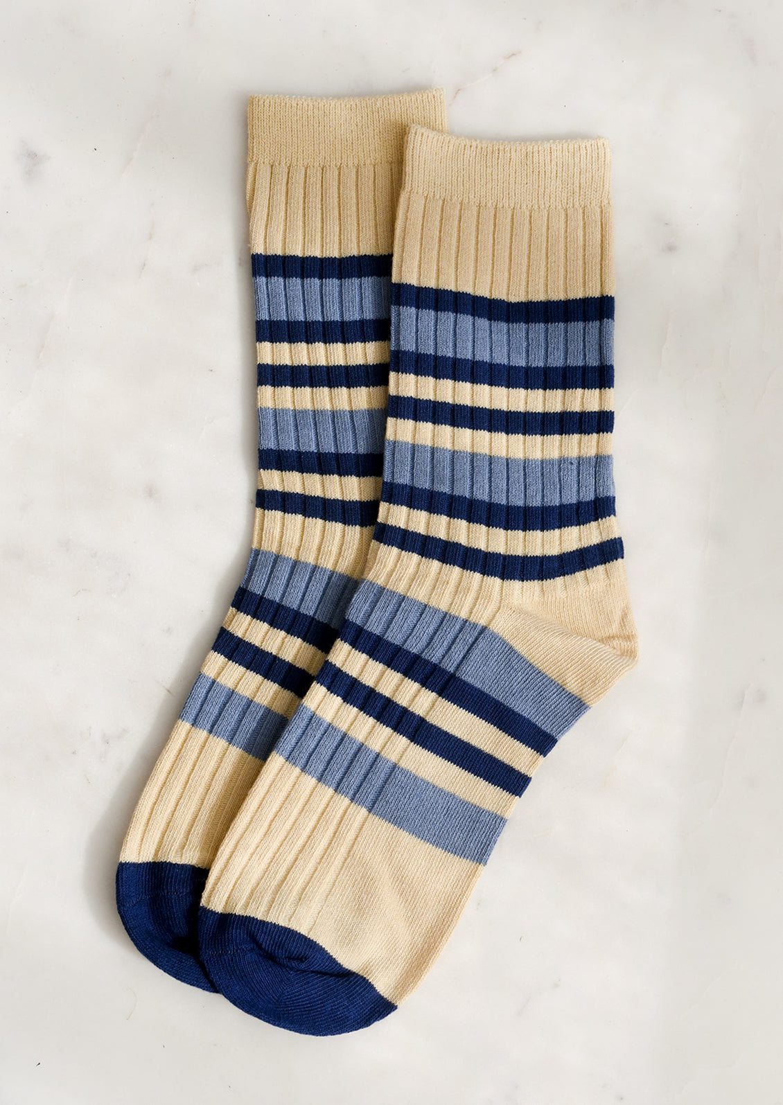 A pair of striped socks in butter yellow, navy blue and denim blue.