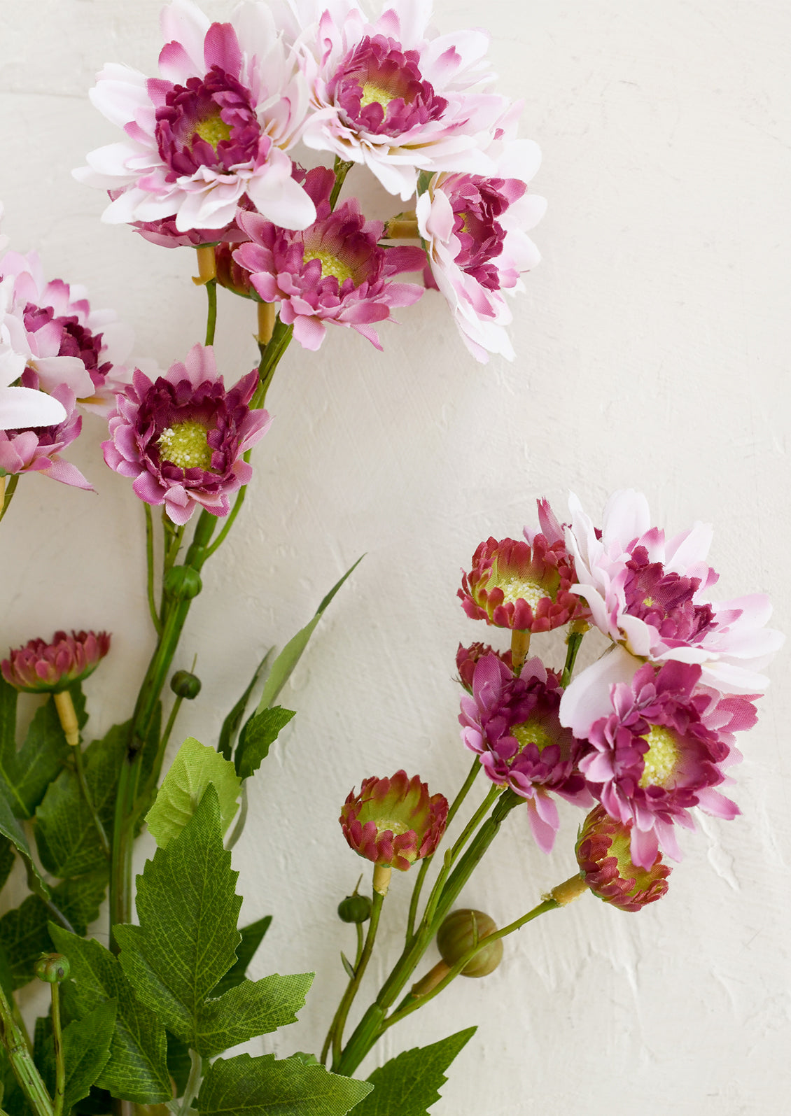 Artificial flower branch with pink and purple flowers on a white background