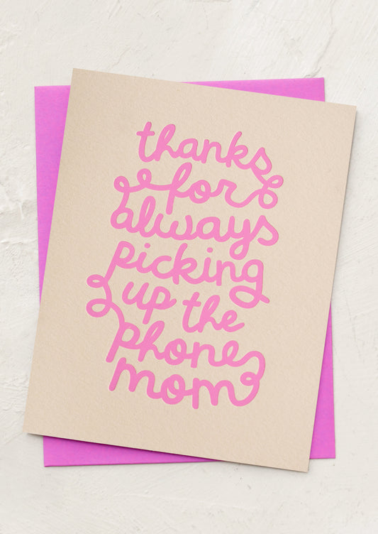 Card with pink text on beige paper over a pink envelope, on a light gray background