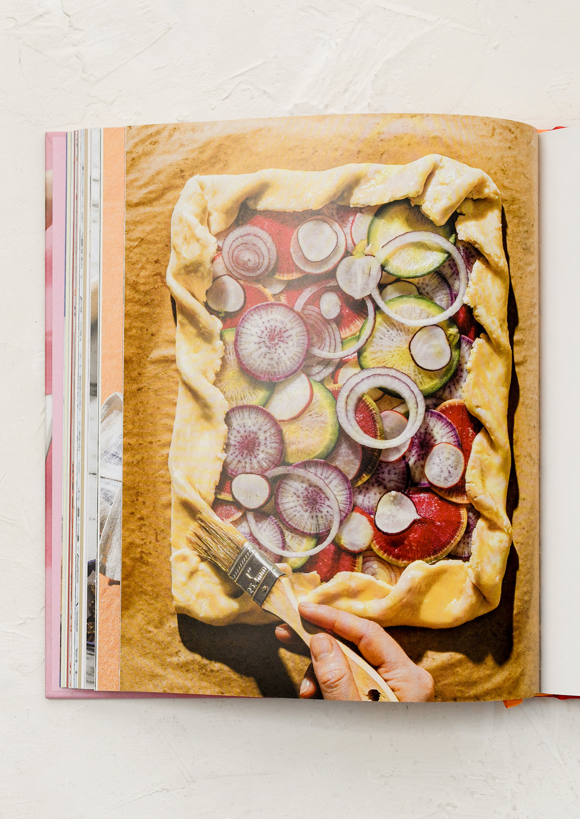 Open cookbook showing a galette with vegetables on a white background