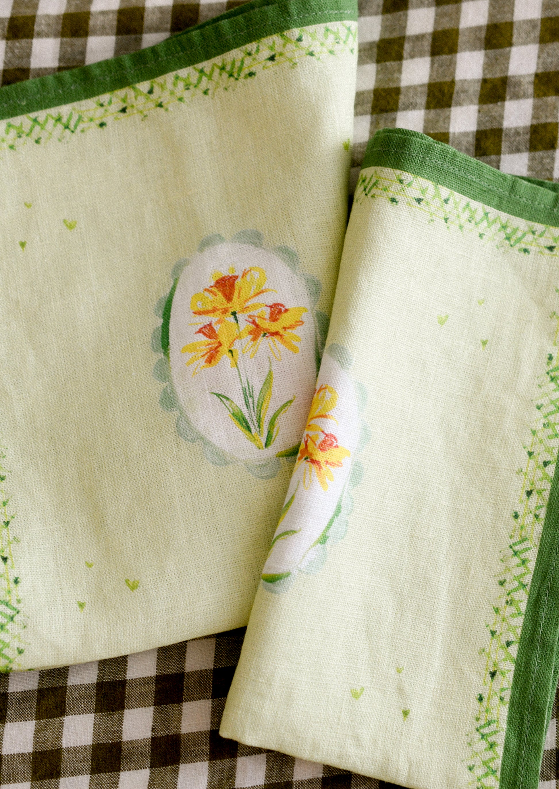 Two green linen napkins with printed daffodil motif.