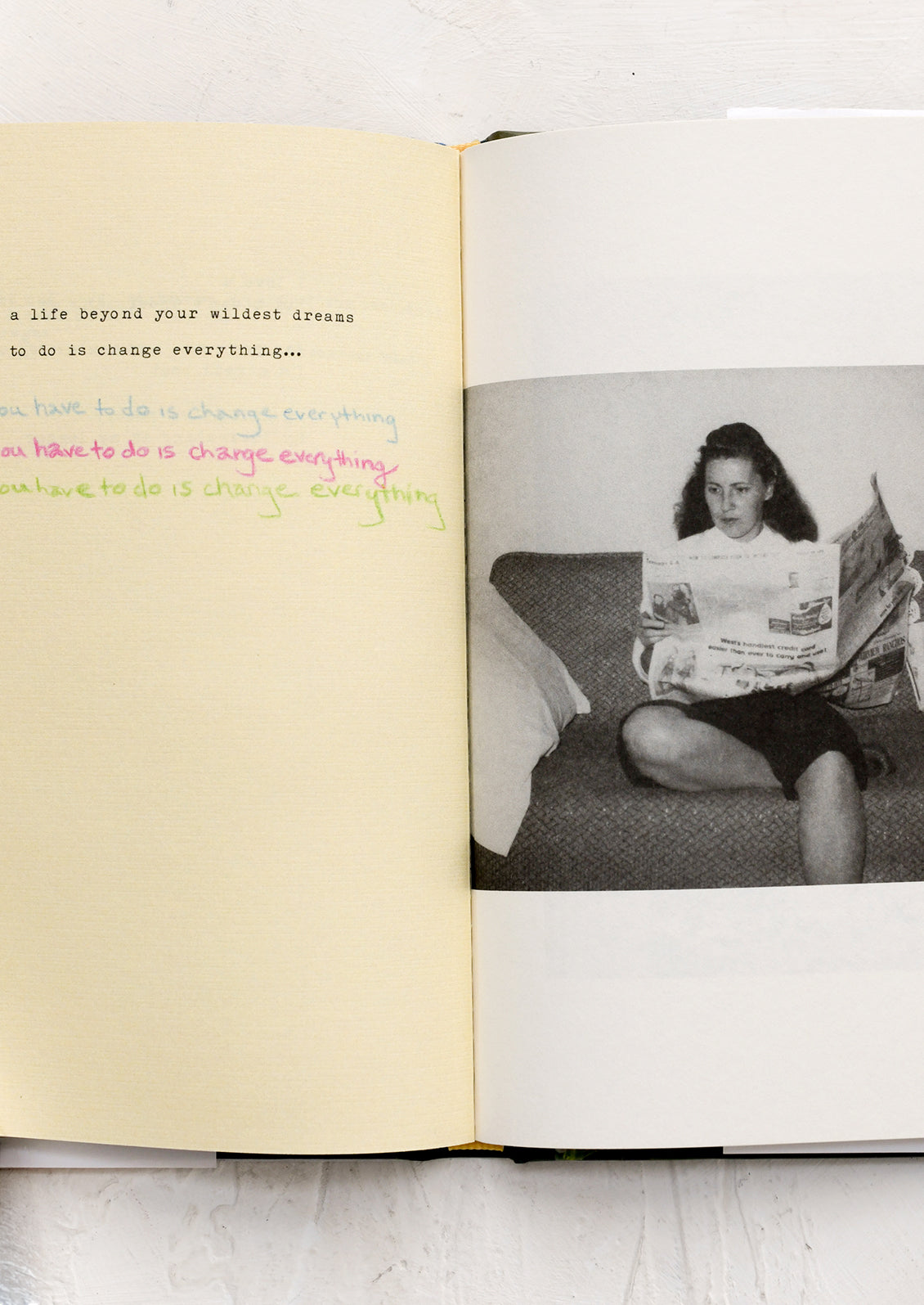 Open book with a black and white photo of a woman reading a newspaper on a couch.