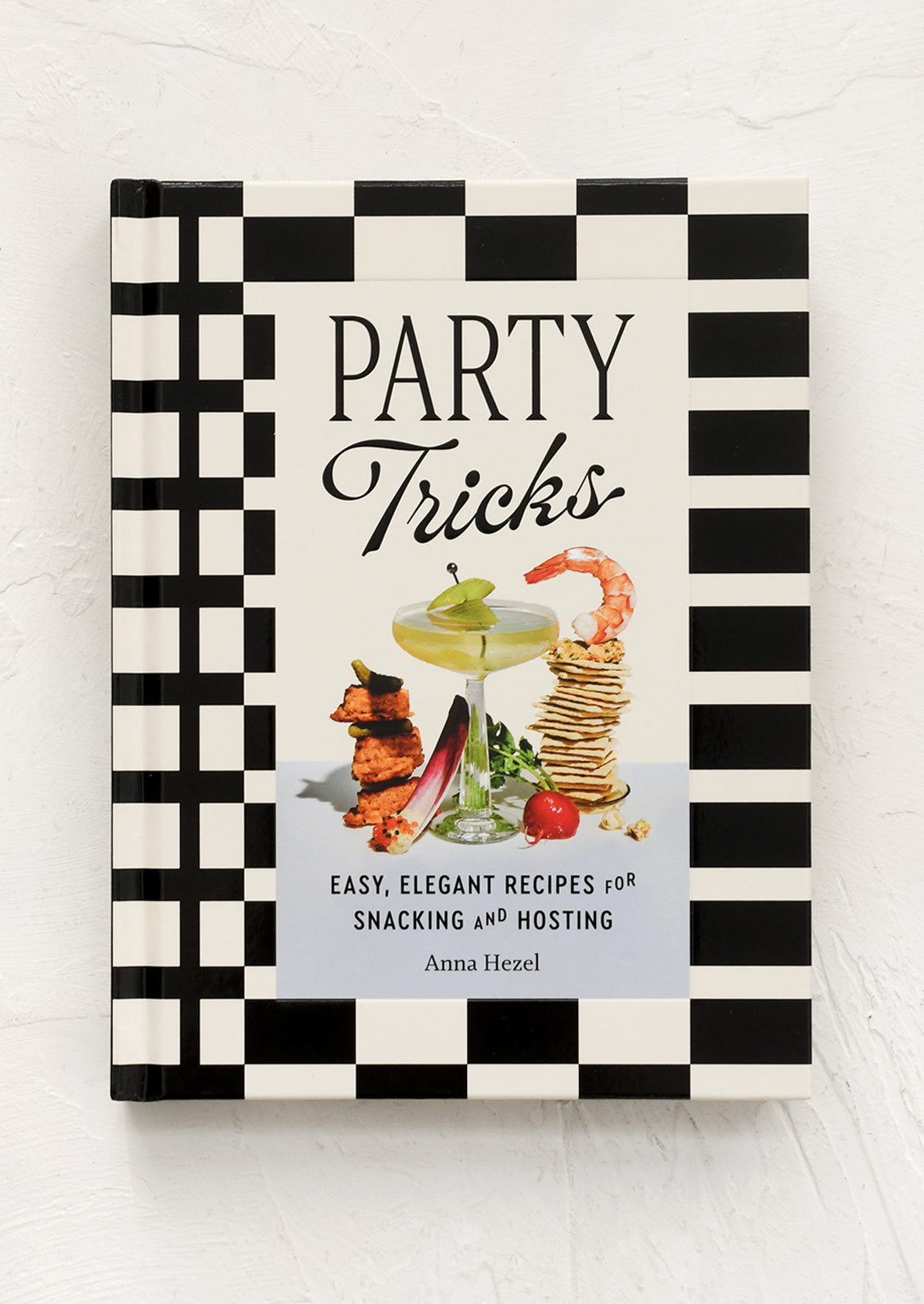 Book titled 'Party Tricks' with black and white checkered design on a light wooden surface