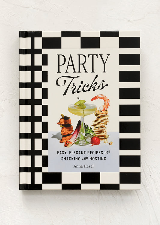 Book titled 'Party Tricks' with black and white checkered design on a light wooden surface