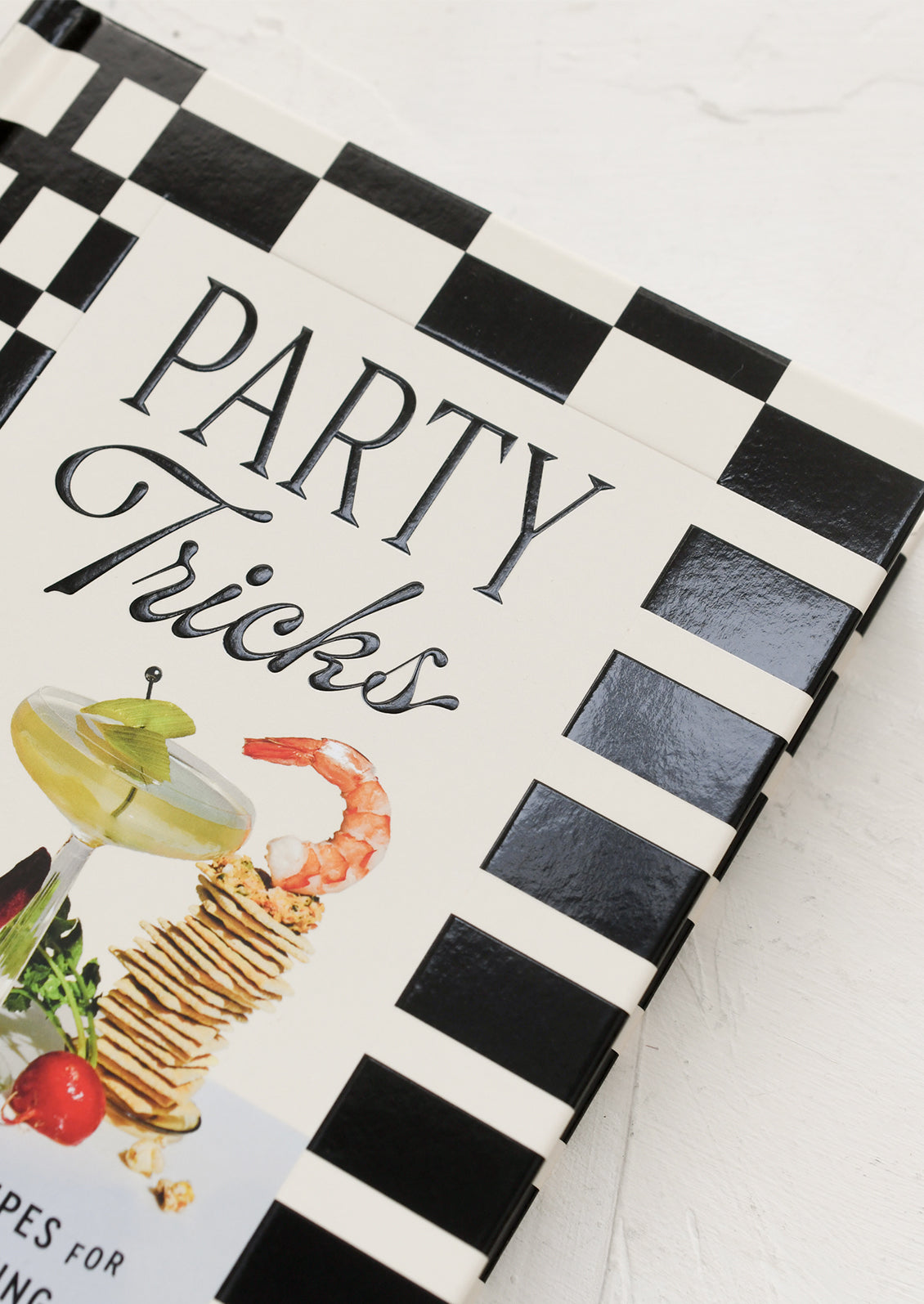 Book titled 'Party Tricks' with black and white checkered design on a white surface
