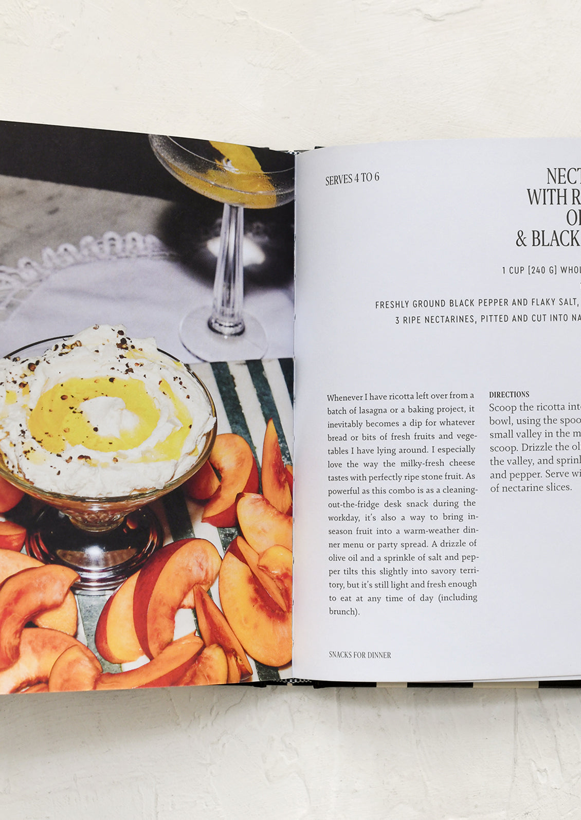Open cookbook showing a recipe for a dessert with a glass of wine and peaches.