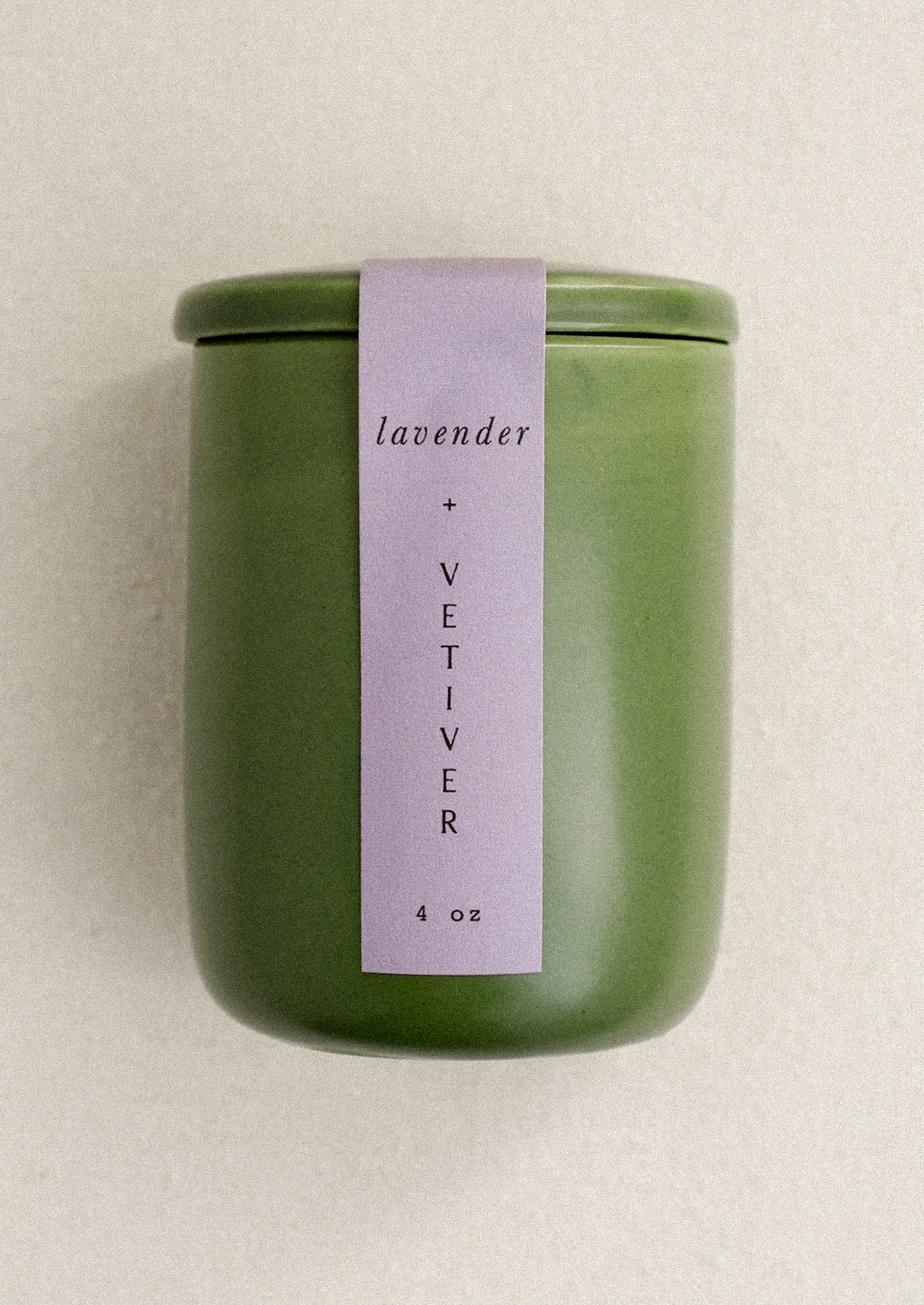 Green candle with a lavender and vetiver label on a beige background