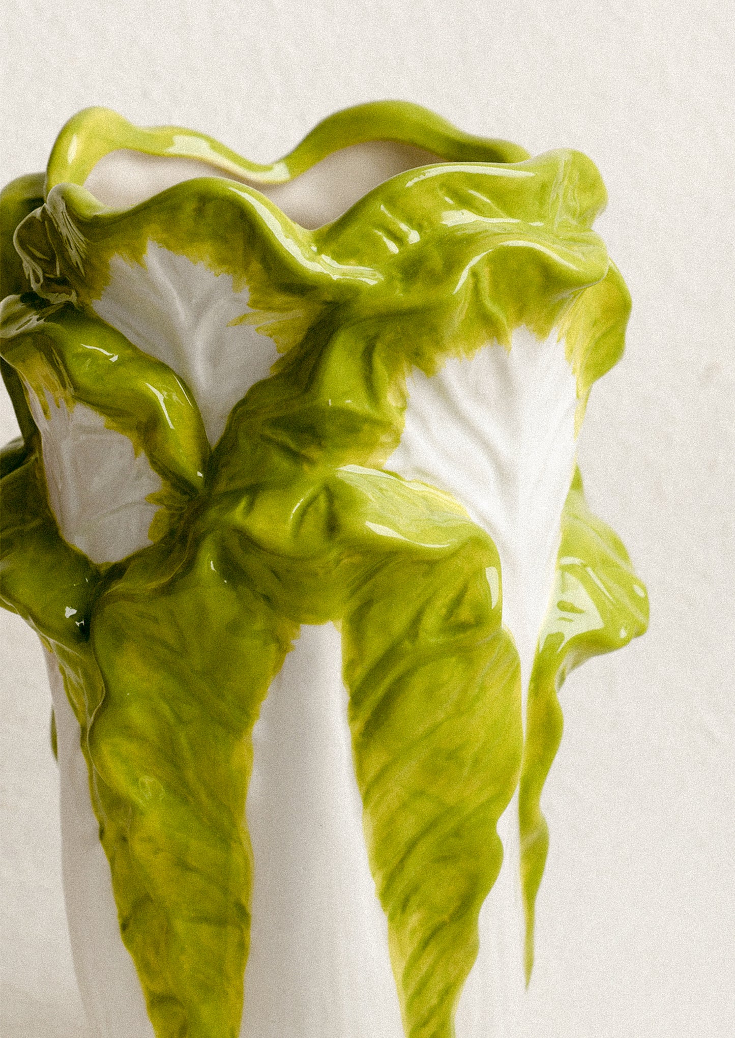 Green ceramic vase with wavy design on a white background