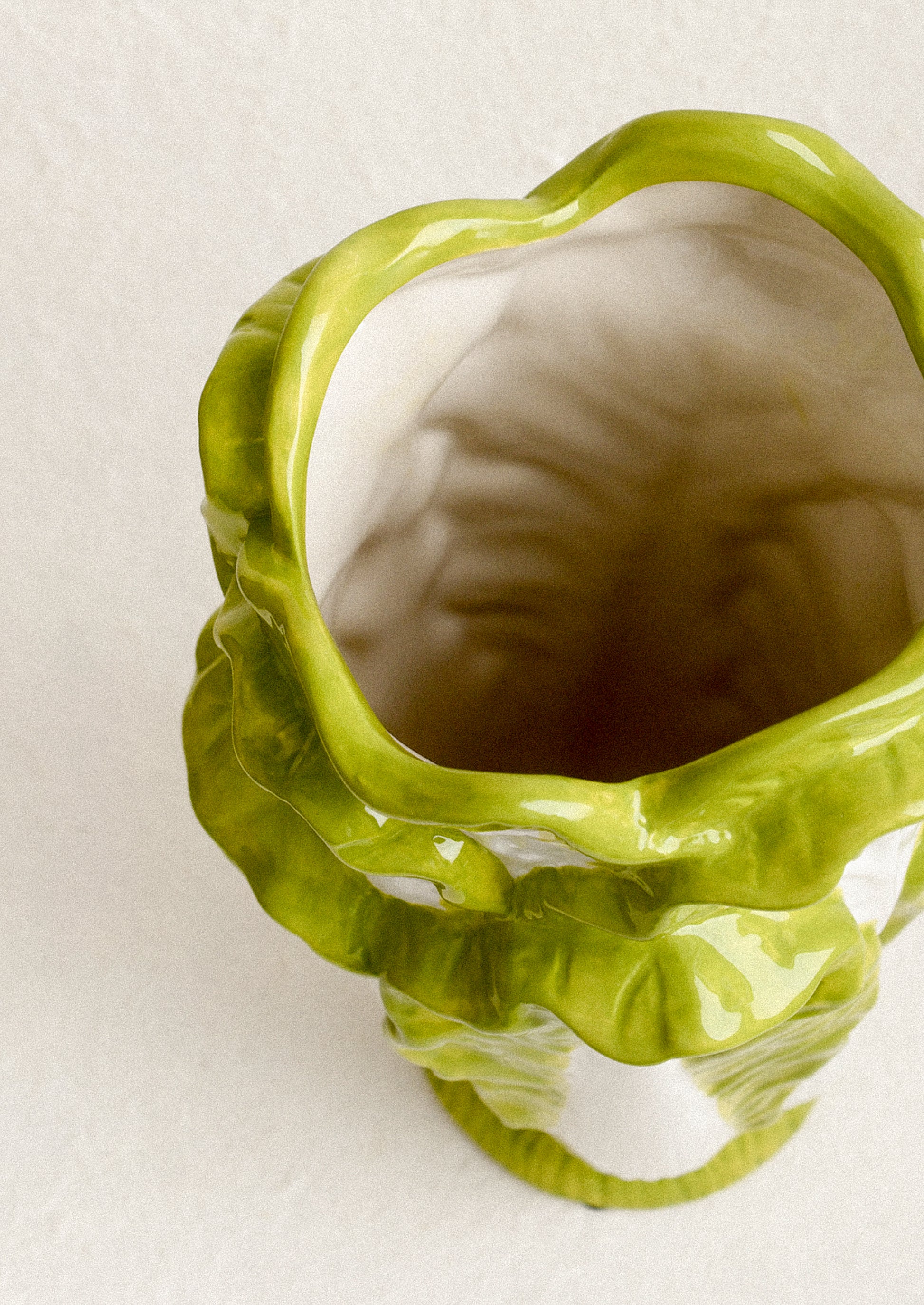 Green ceramic vase with wavy design on a white background