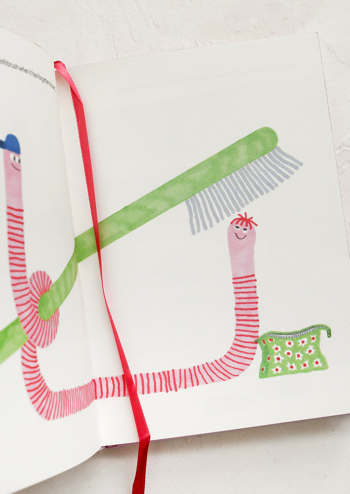 Children's illustration of a red worm with a green hat, a green broom, and a pink ribbon on a white background.