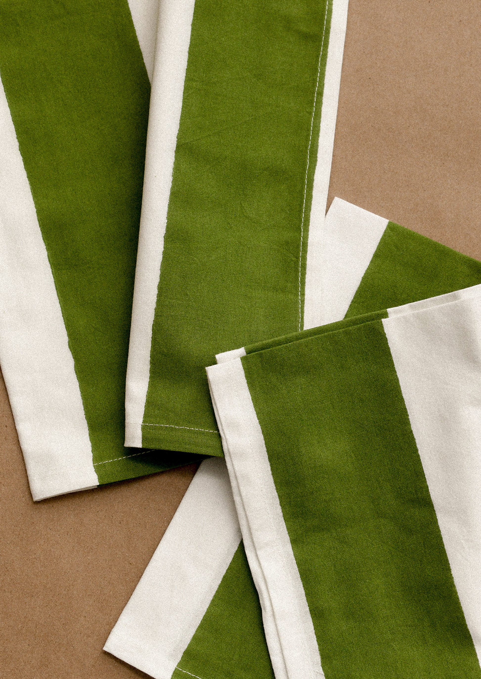 Green and white striped fabric strips on a brown background