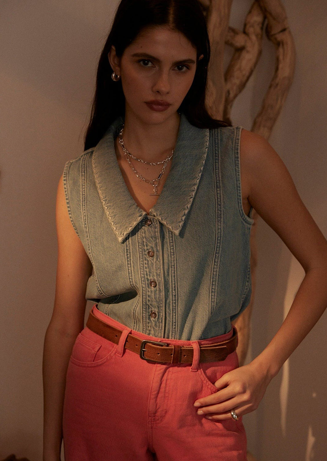 A sleeveless button front top with pointed collar, in light wash denim.