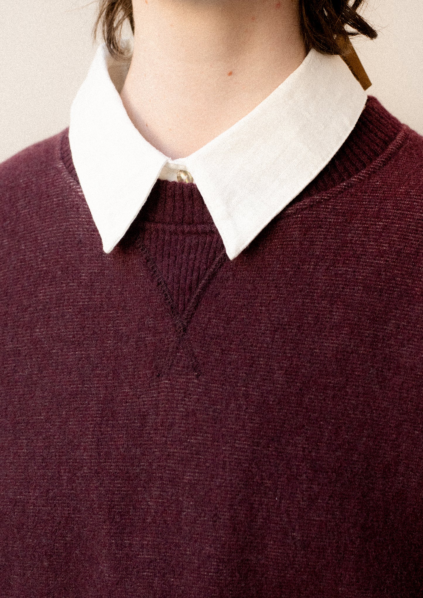 A woman wearing a sweater in burgundy with sweatshirt style silhouette.