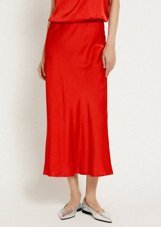 A woman wearing a red flowy sateen skirt.