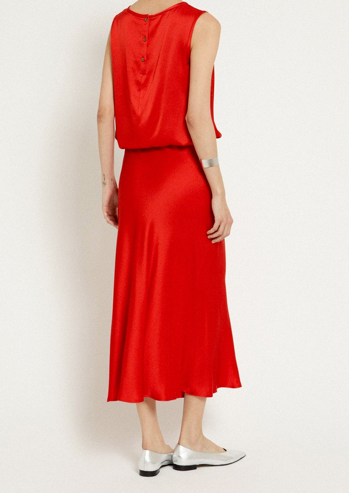 A woman wearing a red flowy sateen skirt.