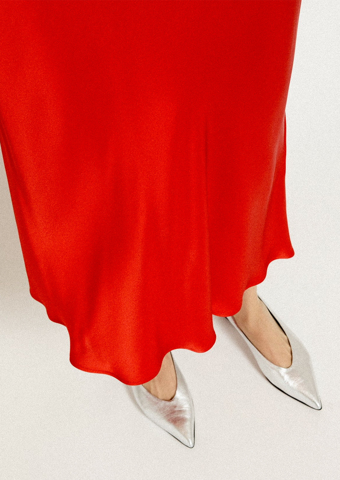 A woman wearing a red flowy sateen skirt.