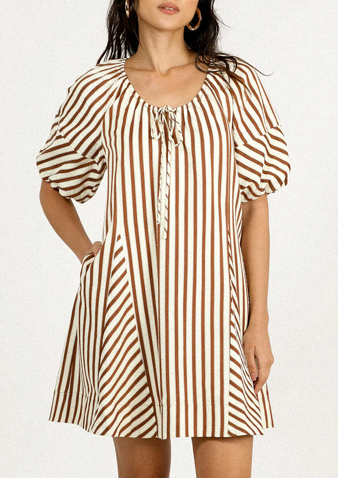 A person wearing a short dress in brown and cream vertical stripe pattern.