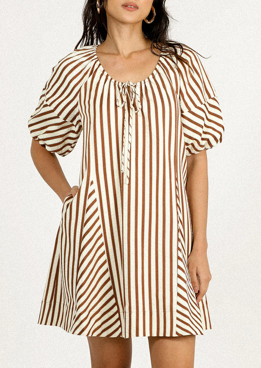 A person wearing a short dress in brown and cream vertical stripe pattern.