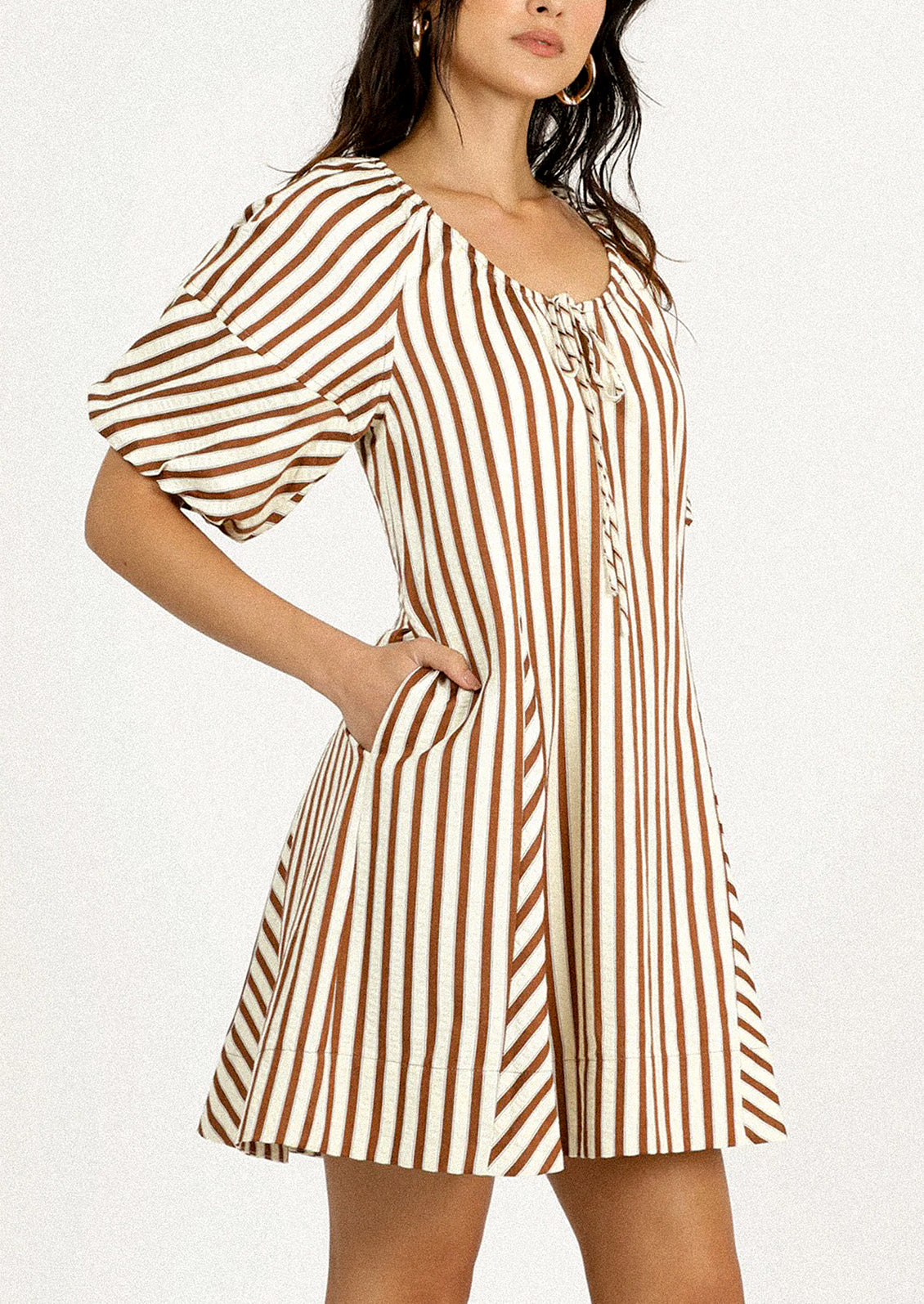 A person wearing a short dress in brown and cream vertical stripe pattern.