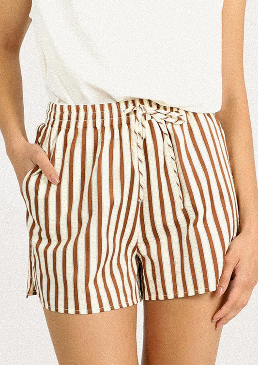 A person wearing a pair of brown and cream striped shorts.