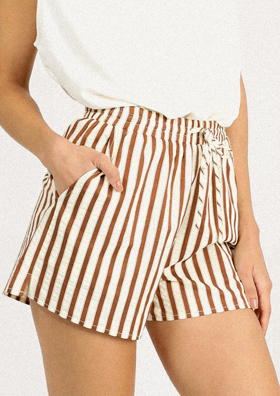 A person wearing a pair of brown and cream striped shorts.
