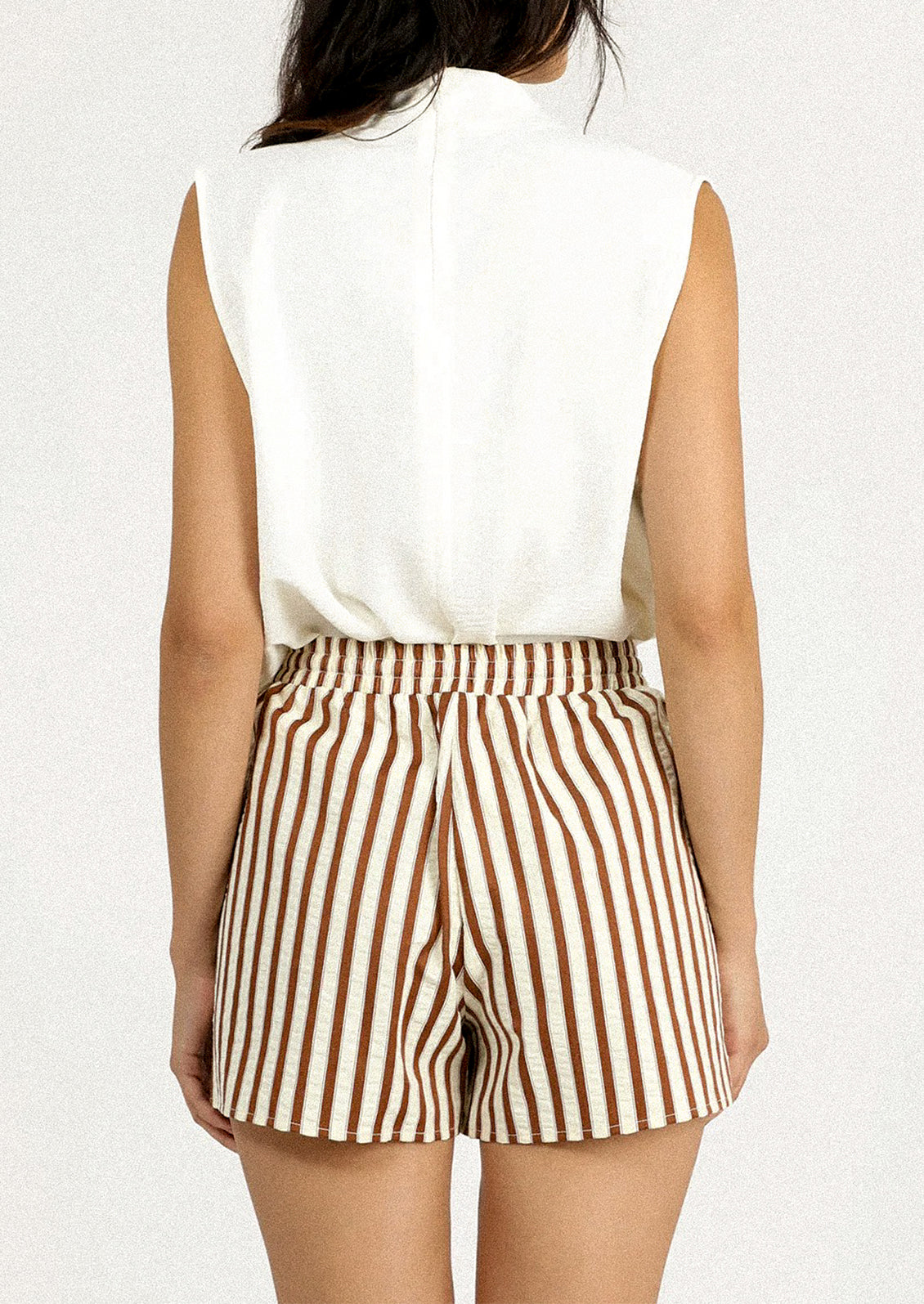 A person wearing a pair of brown and cream striped shorts.