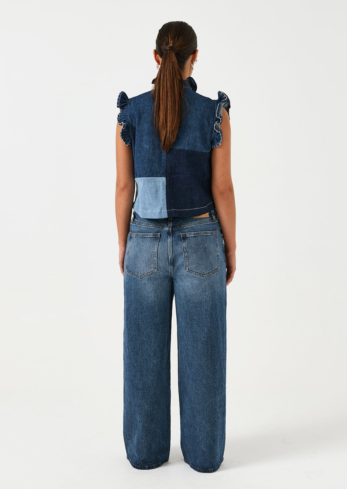 A woman wearing a pair of wide leg jeans in classic medium blue wash.