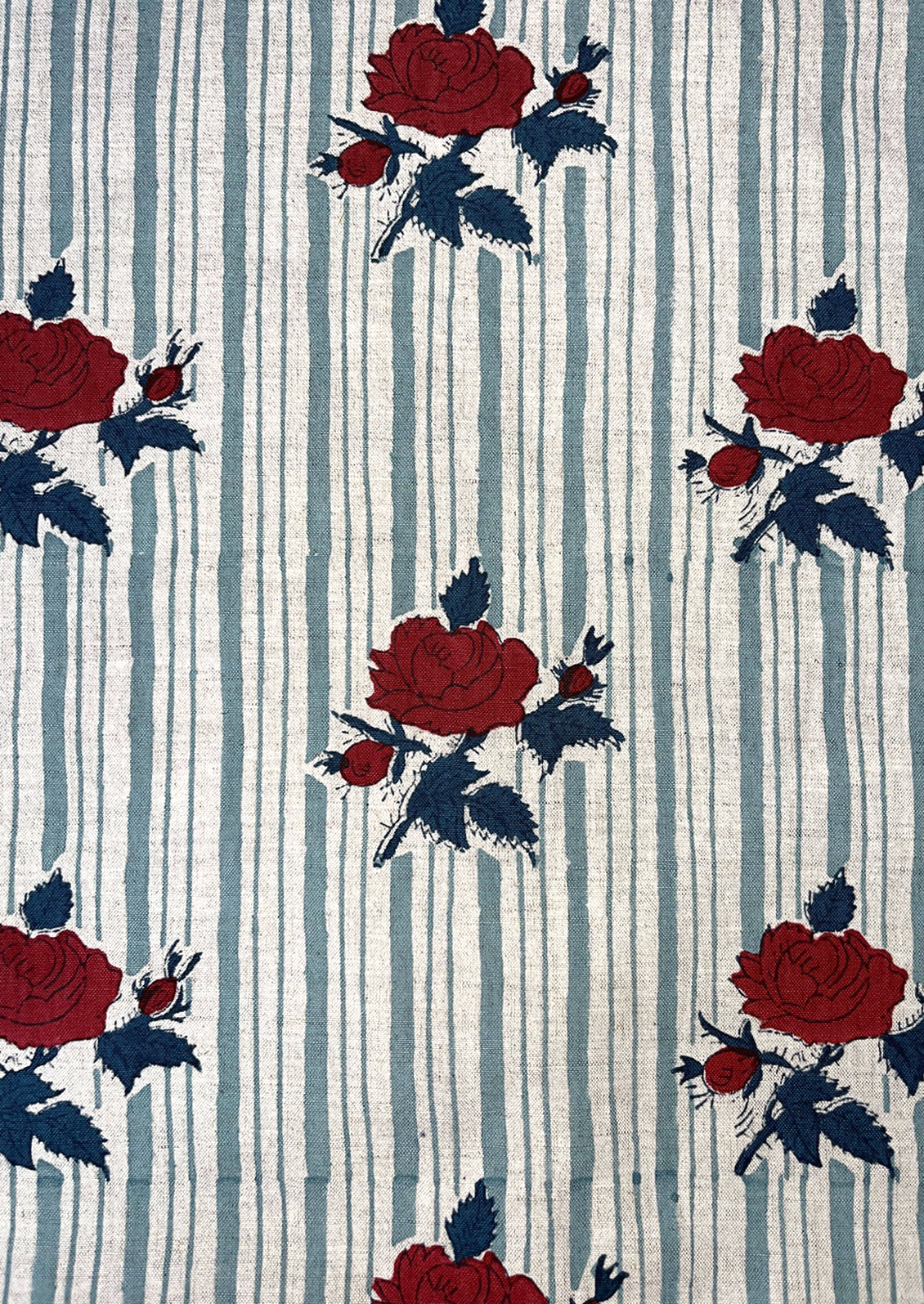 Fabric with red roses and blue leaves on a striped background